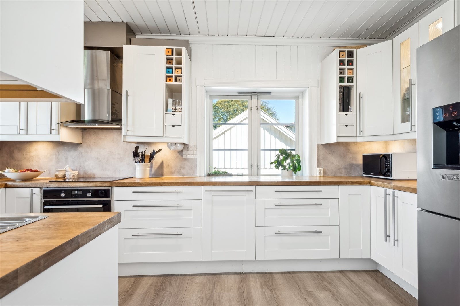 Benkeplaten er i heltre med kjøkkenkran og dobbel vaskekum med avrenningsplate. Det er belysning under overskapene. Galleribilde