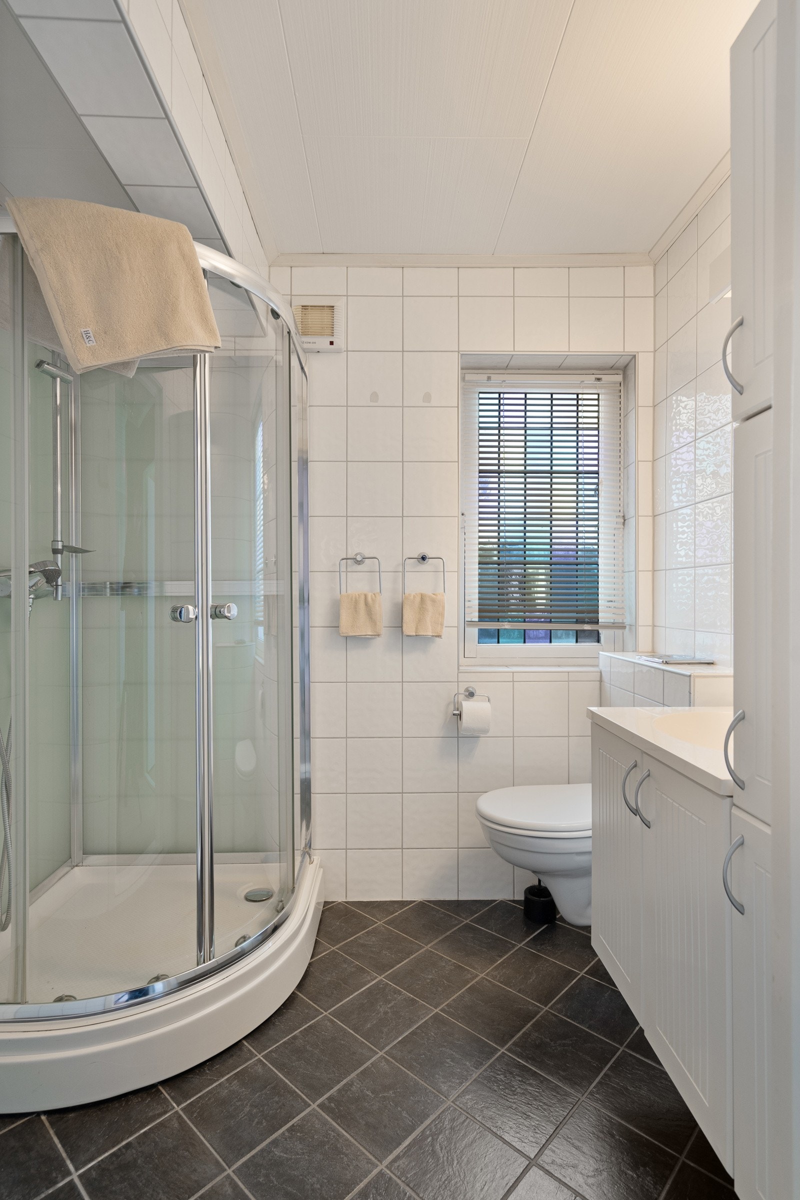 Badet er flislagt og utstyrt med varmekabler i gulv, servant, toalett og dusjløsning. Galleribilde