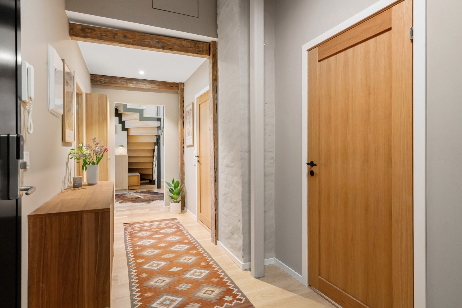 Lys og pen gang/entré med gråmalte vegger, originale, gylne bjelker og enstavs eikeparkett av typen Eik Harmoni på gulvet. Galleribilde