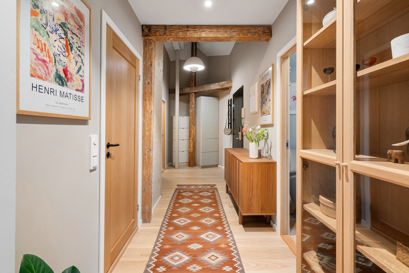 Leiligheten ligger i 5. etasje, og har adkomst via felles oppgang med trapper. Vel inne blir vi ønsket velkommen i en lys og pen entré med gråmalte vegger, originale, gylne bjelker og enstavs eikeparkett av typen Eik Harmoni på gulvet. Galleribilde