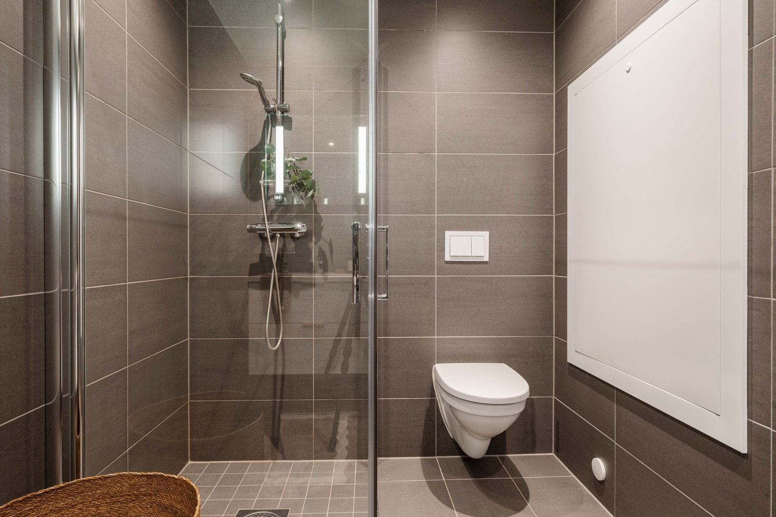 Badet er utstyrt med vegghengt toalett og innfellbare dusjvegger med nedsenket gulv i dusjsonen. Galleribilde