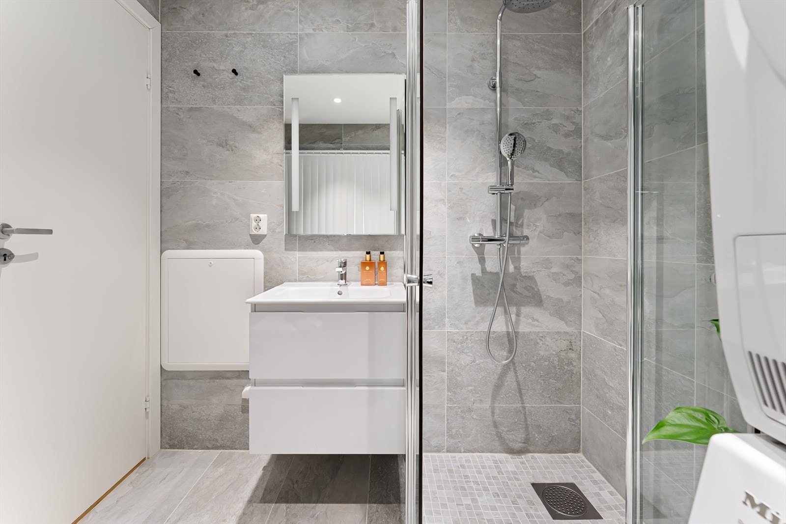 Innredet med regnfalldusk, servant med skuffer, ledspeil og veggmontert toalett. Galleribilde