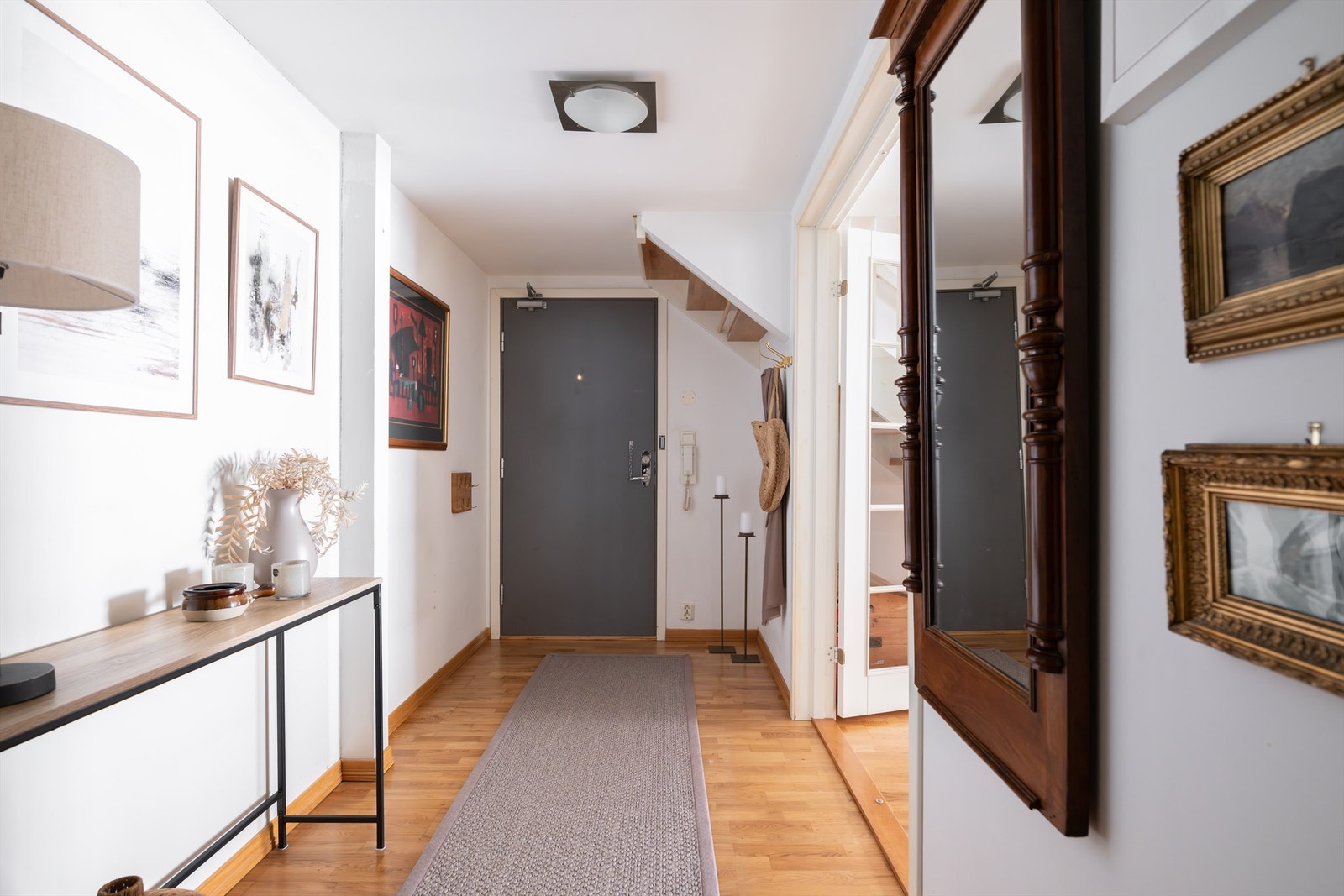 Velkommen inn i en lys og innbydende entré med parkett på gulv og malte, slette veggflater. Galleribilde