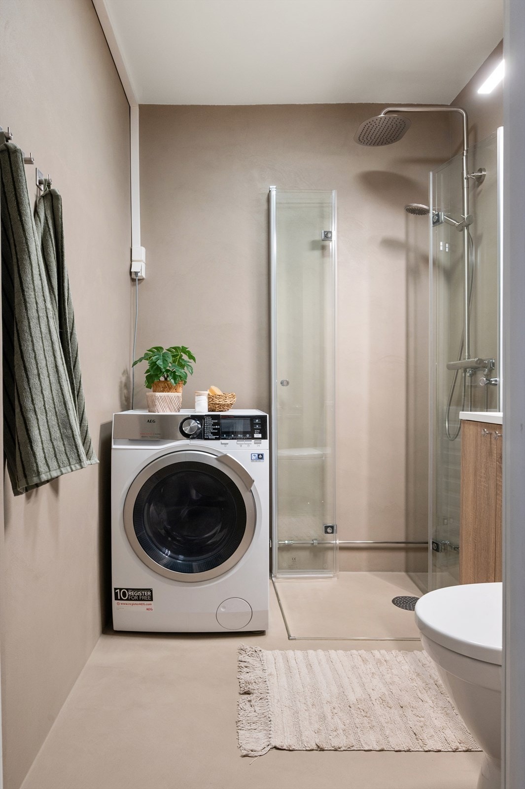 Mikrosementen i en delikat beige tone bidrar til en lun og elegant atmosfære. Elektriske varmekabler i gulv og opplegg for vaskesøyle. Galleribilde