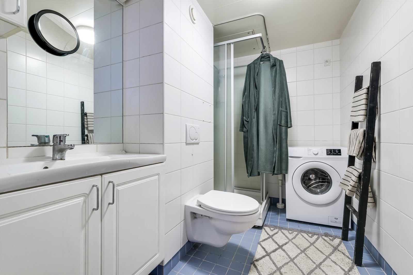 Badet inneholder servant med underskap, vegghengt toalett, dusjkabinett og opplegg for vaskemaskin. Galleribilde