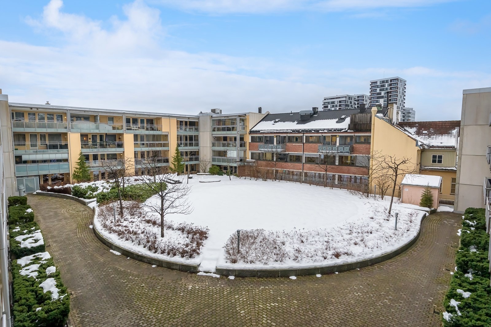 Sameiet har et rolig og pent atrium med sitteplasser, trær og sirkelformet plen. Galleribilde