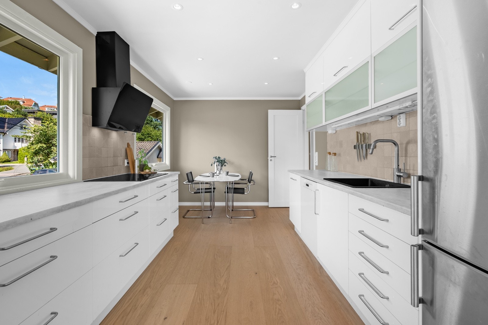 Moderne innredning med glatte, folierte fronter, lys benkeplate med nedfelt kum i kompositt og uttrekkbar kran Galleribilde