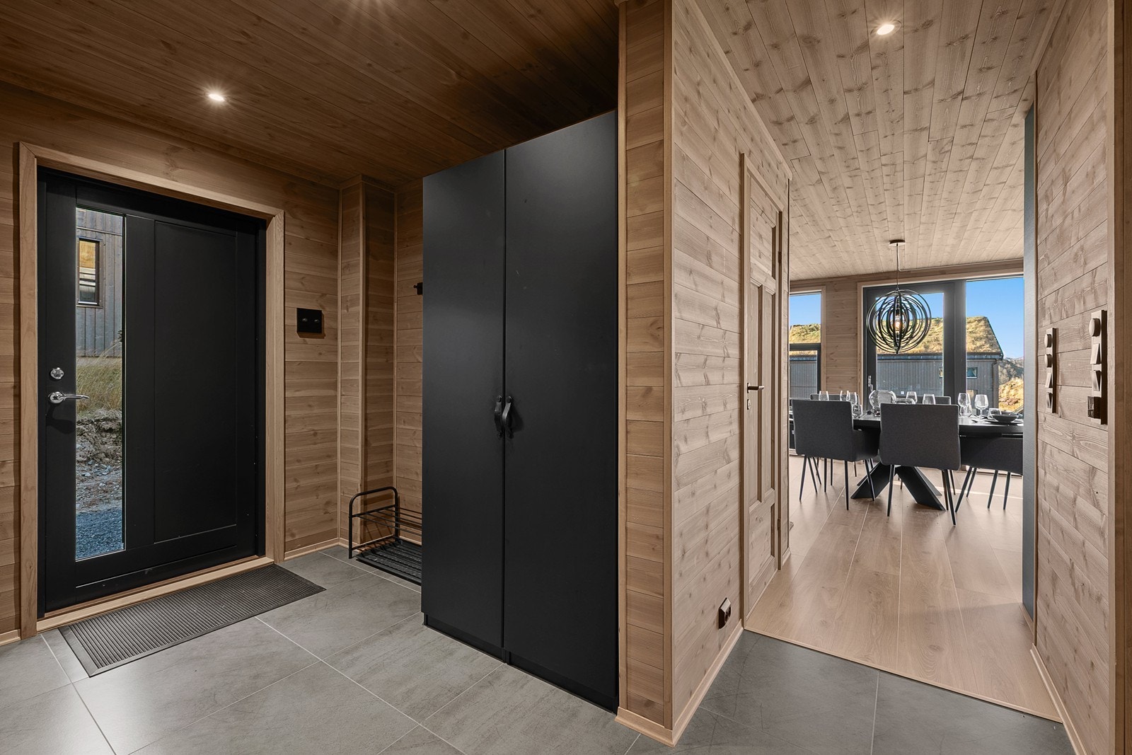 Man ankommer hytta via en pen, flislagt gang med varmekabler i gulv og downlights i himlingen. Her er det god plass til å henge fra seg. Galleribilde