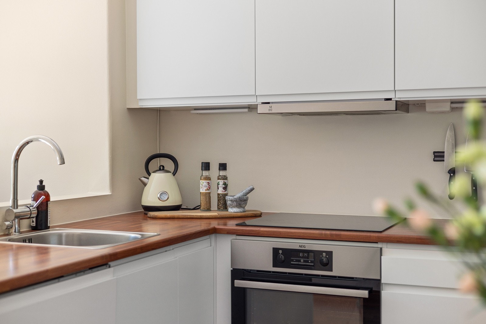 Innredningen har hvite glatte fronter og laminert benkeplate med nedfelt oppvaskkum. Praktisk med takhøye overskap med belysning under. Galleribilde