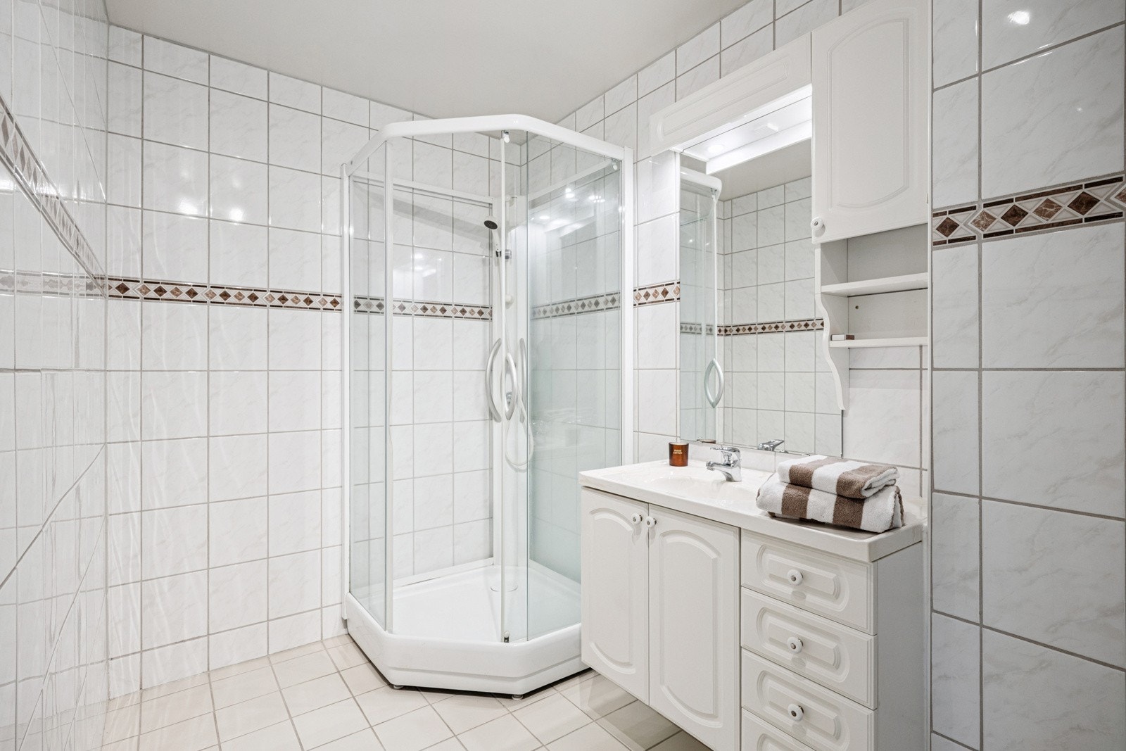 Flislagt bad med varmekabler og innredet med dusjkabinett, servant nedfelt i innredning og toalett. Galleribilde