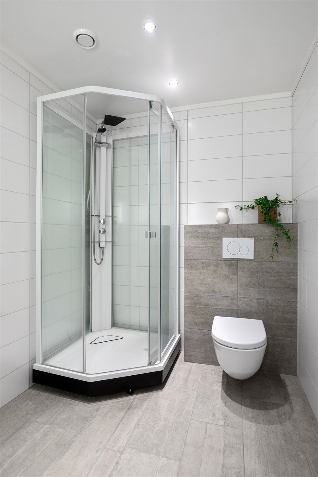 Badet er utstyrt med servant, speil med lys, dusjkabinett og toalett Galleribilde