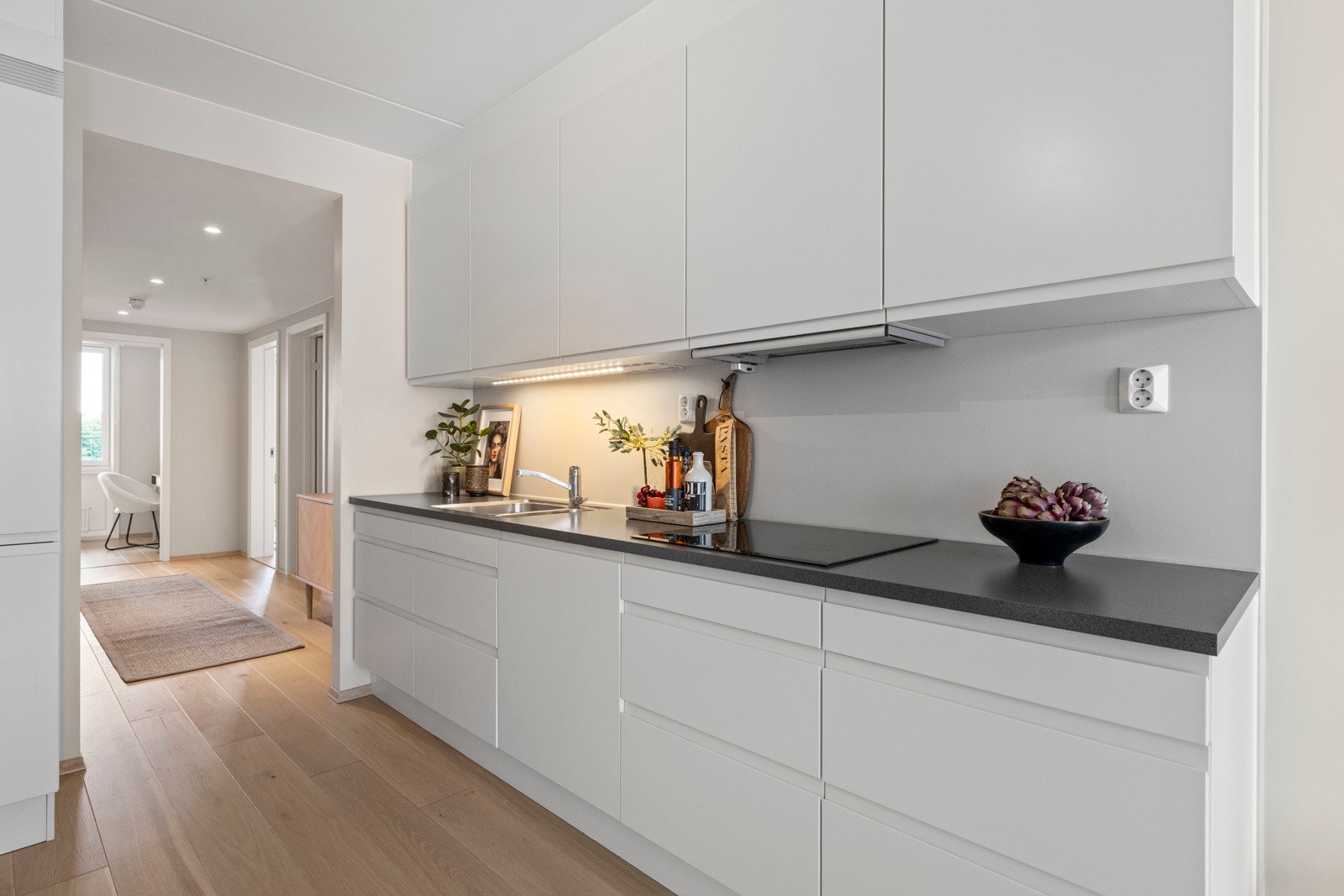 Kjøkkenet er utstyrt med glatt innredning, lys under overskap og benkeplate i laminat med underlimt oppvaskkum. Galleribilde