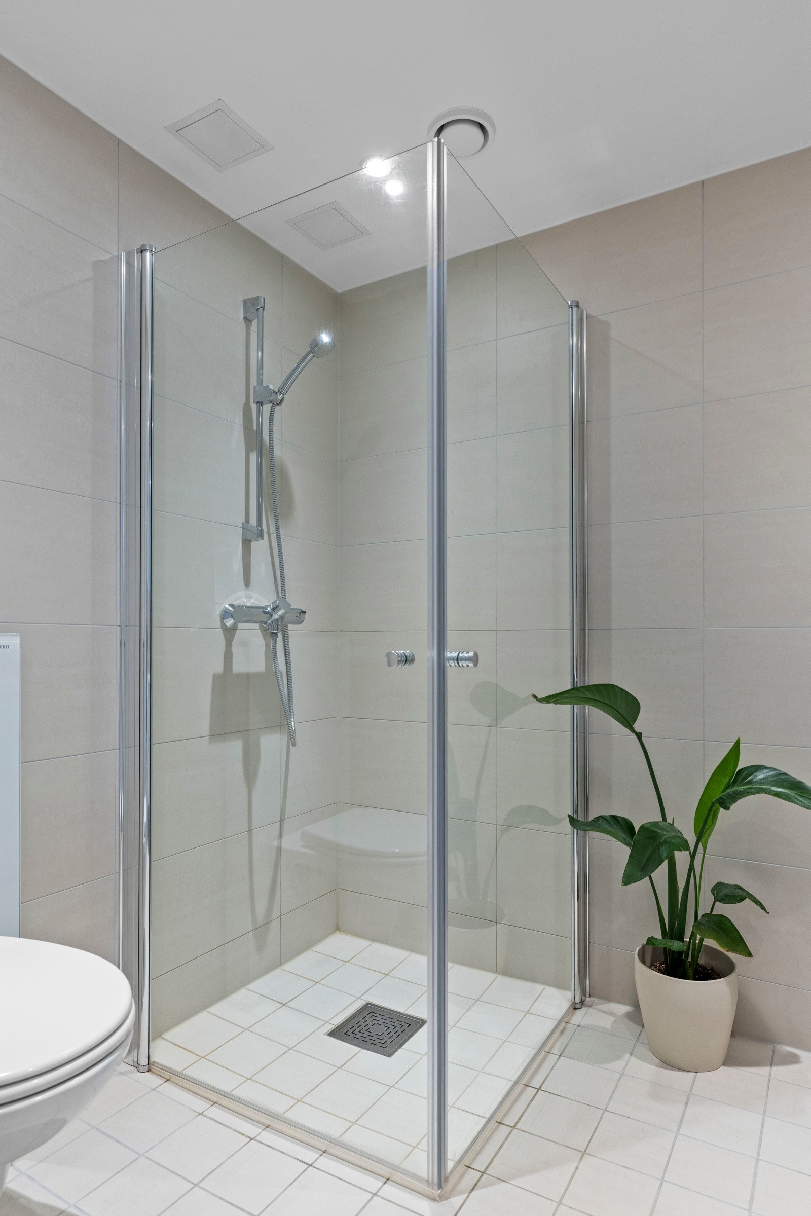 Badet er videre innredet med speilskap med lys, vegghengt toalett med utenpåliggende sisterne og dusj i hjørnet bak svingbare glassvegger. Galleribilde