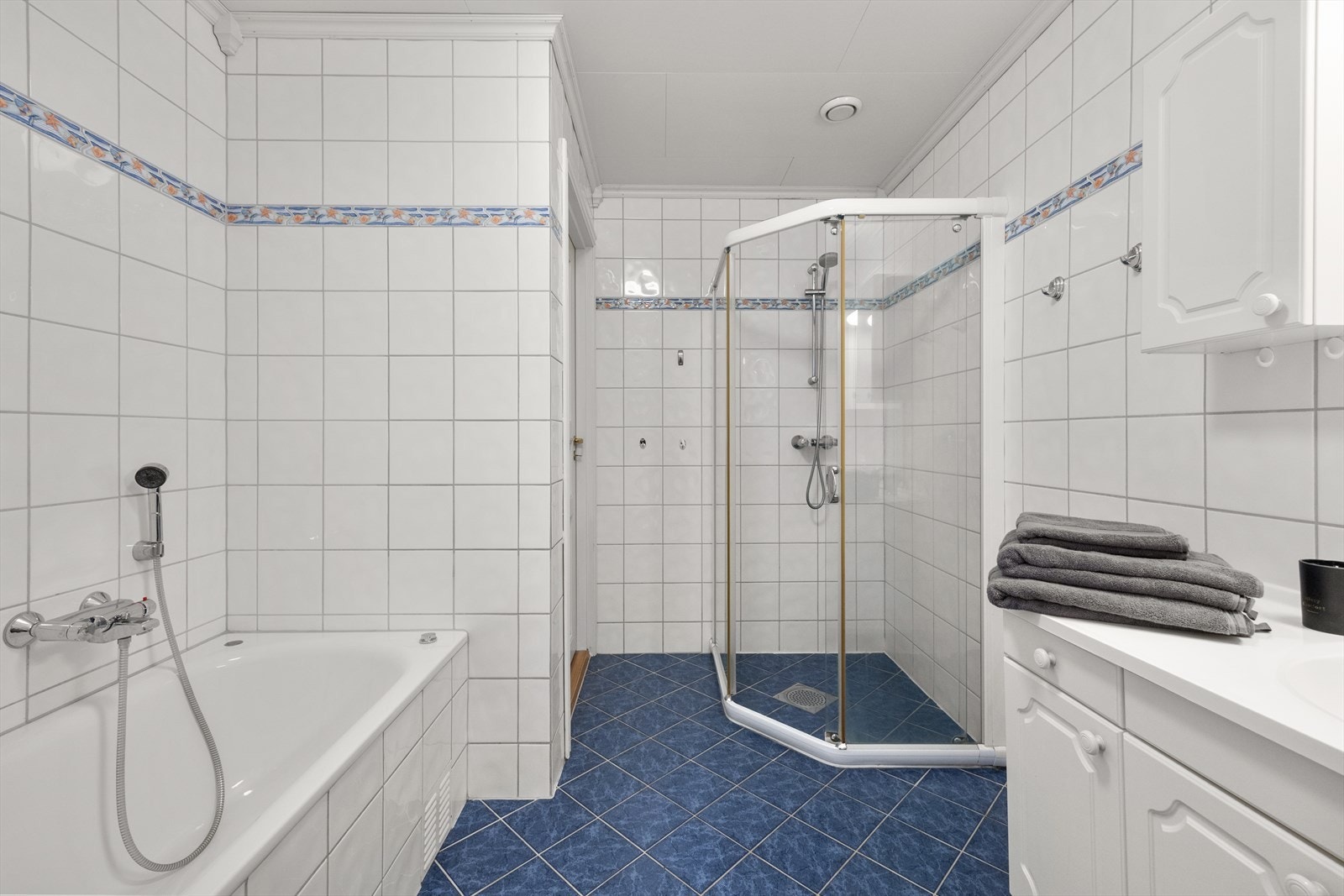 Rommet er utstyrt med skap med glatte fronter, speil over servant, klosett, badekar og dusj på gulv. Galleribilde