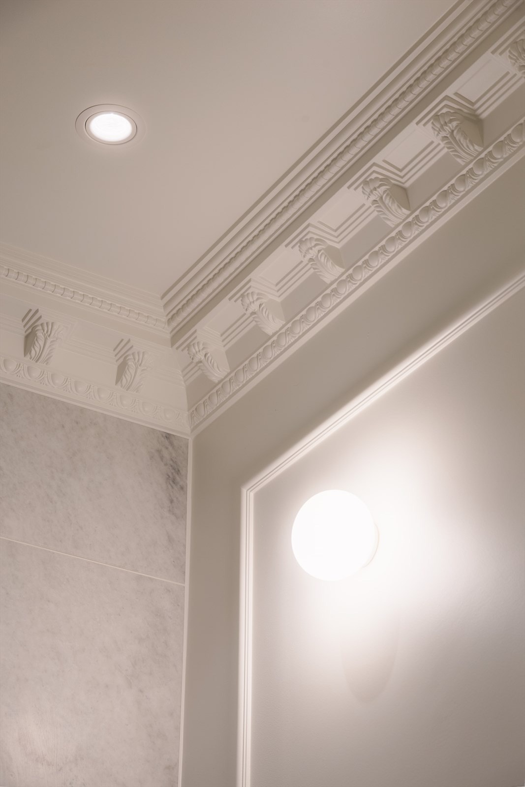 Veggene er delvis flislagt, mens himlingen er malt og utsmykket med elegant stukkatur, noe som gir rommet et klassisk og tidløst preg. Galleribilde