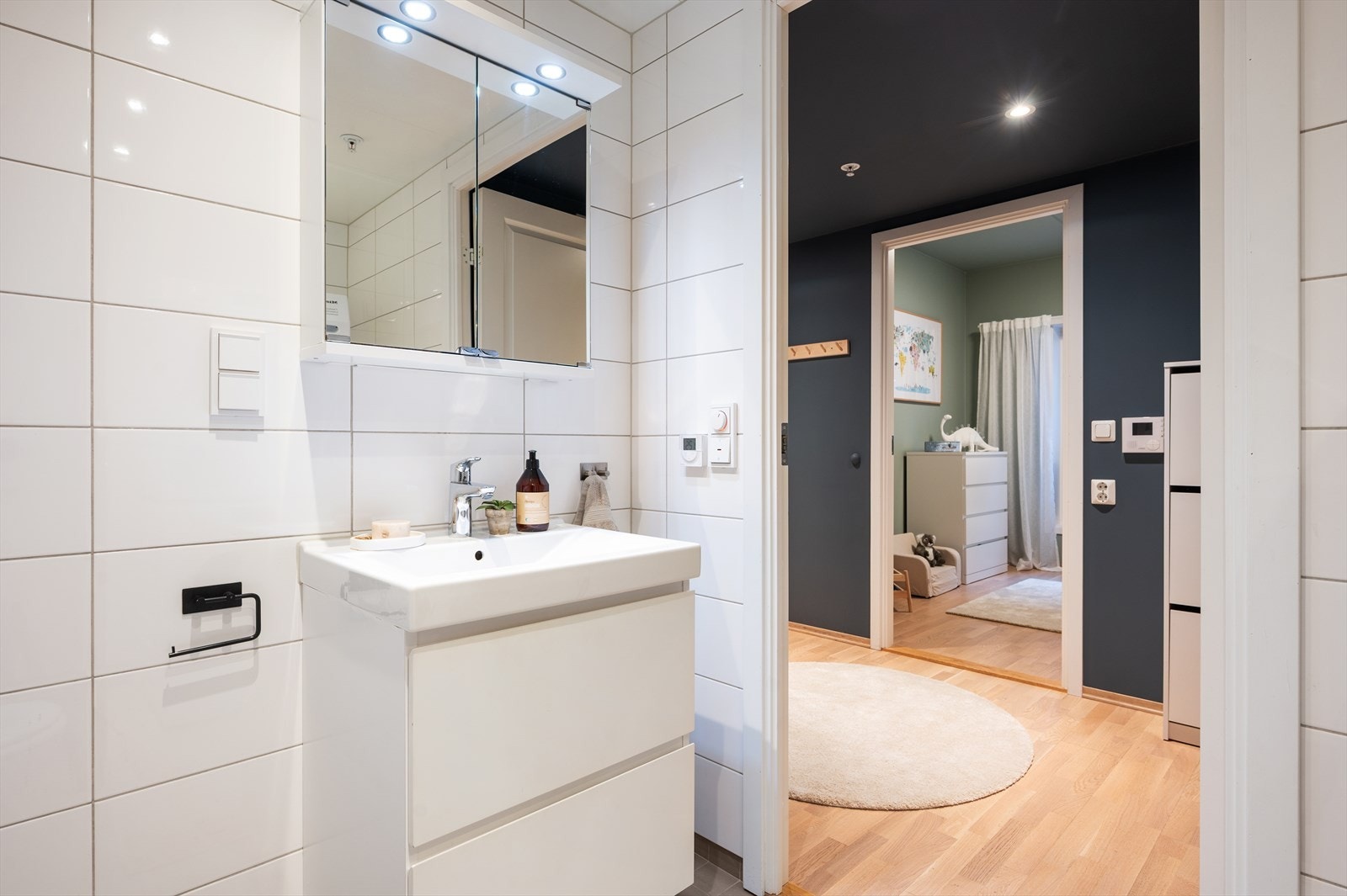 Badet er innredet med vegghengt toalett, servant nedfelt i innredning, speilskap med lys og dusjhjørne med svingbare glassdører. Galleribilde