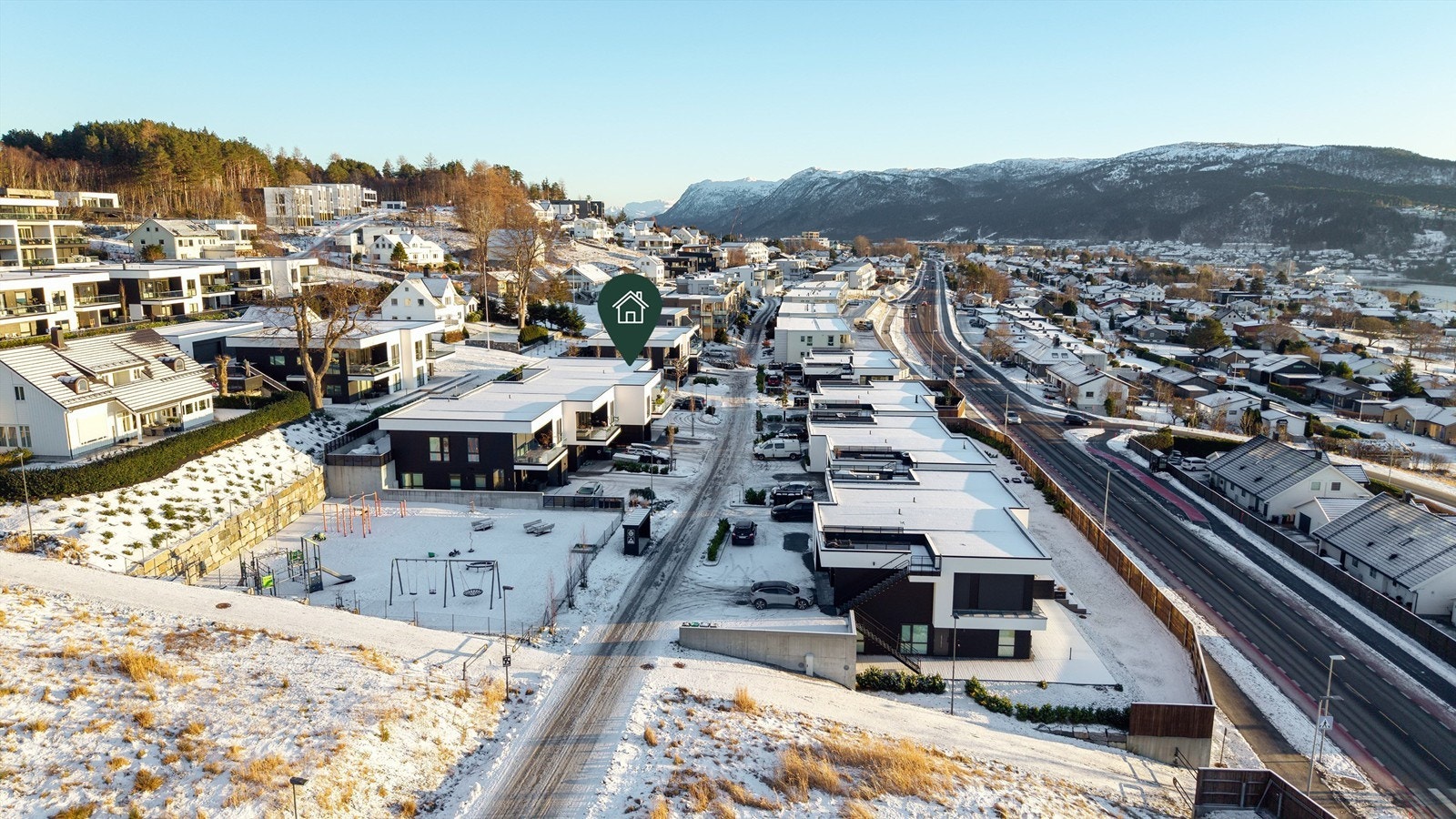Dronebilde av boligområdet tatt fra vest mot øst - stor lekeplass like vest for boligen. Galleribilde
