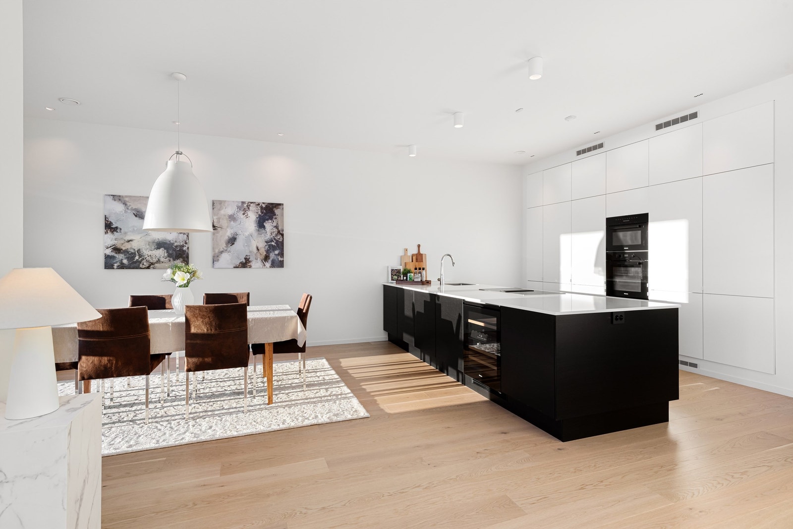 Kjøkken i åpen løsning mot stue med stor kjøkkenøy Galleribilde