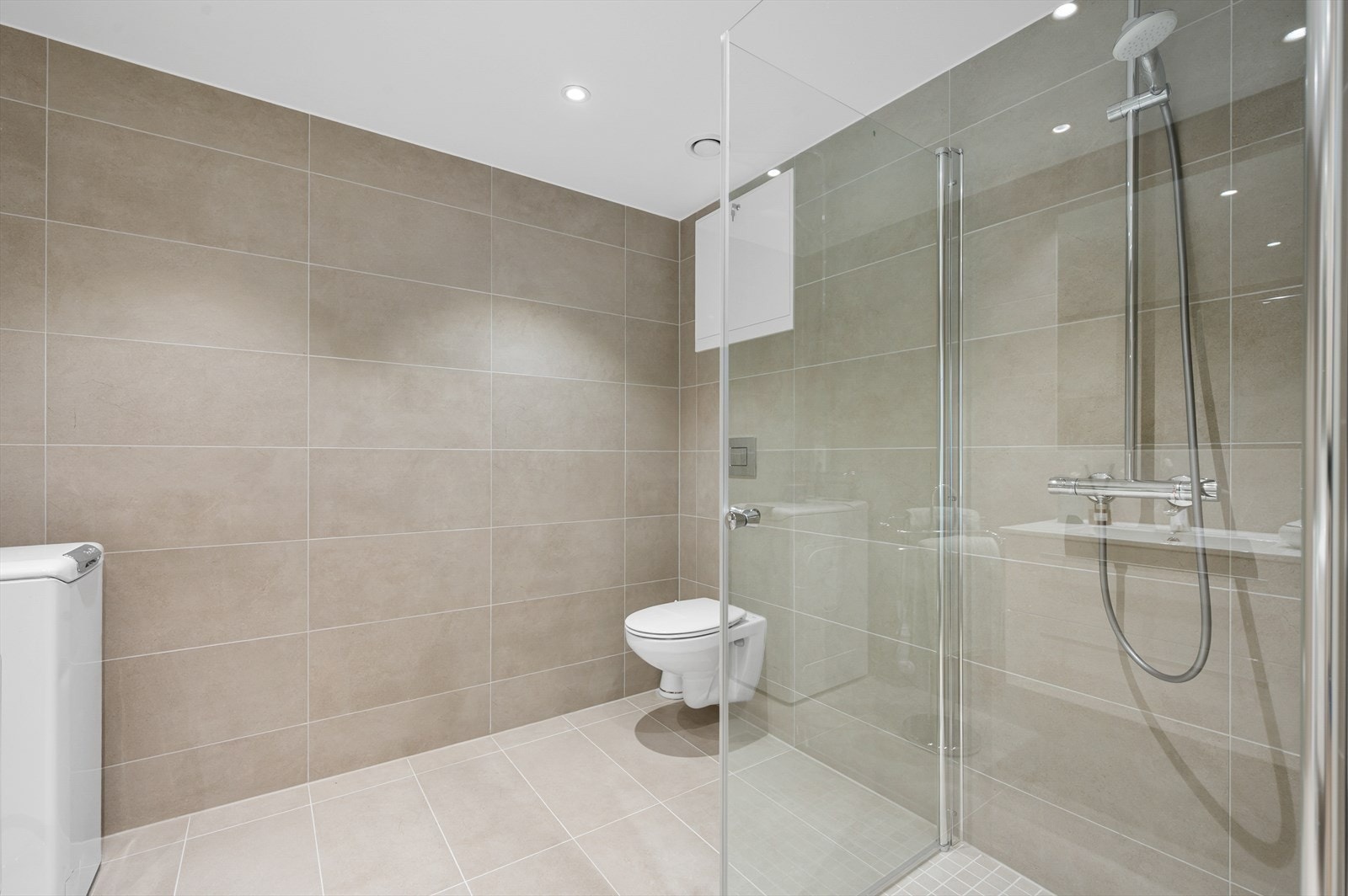 Baderomsinnredningen har hvite fronter og består av en heldekkende servant på en skuffeseksjon og et stort, innfliset speil. Galleribilde