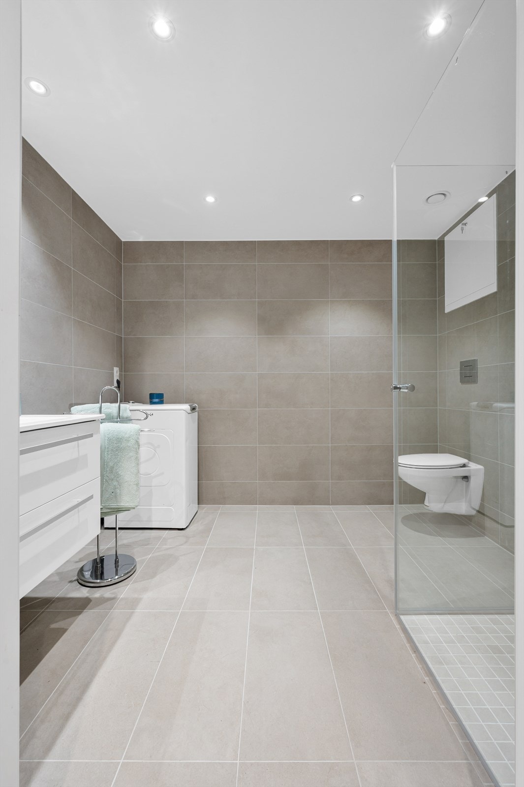 I tillegg til et vegghengt toalett har badet opplegg for vaskemaskin og et dusjhjørne med innfellbare glassdører. Galleribilde