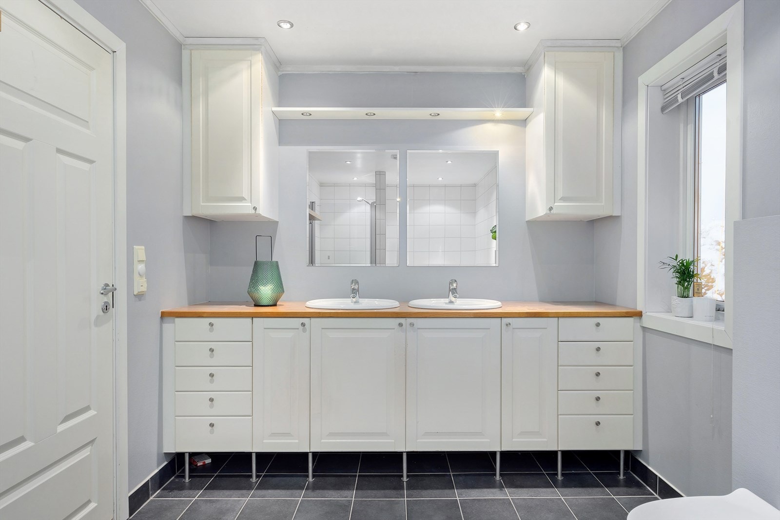 Badet inneholder badekar, dusjnisje, vegghengt toalett og dobbel servant med god oppbevaringsplass i stor innredning med skap og skuffer. Galleribilde