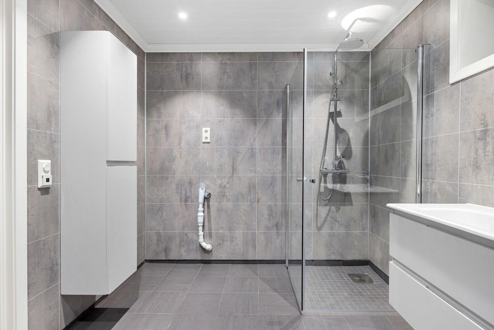 Moderne bad med flislagt gulv med varmekabler og downlights i himling. Galleribilde