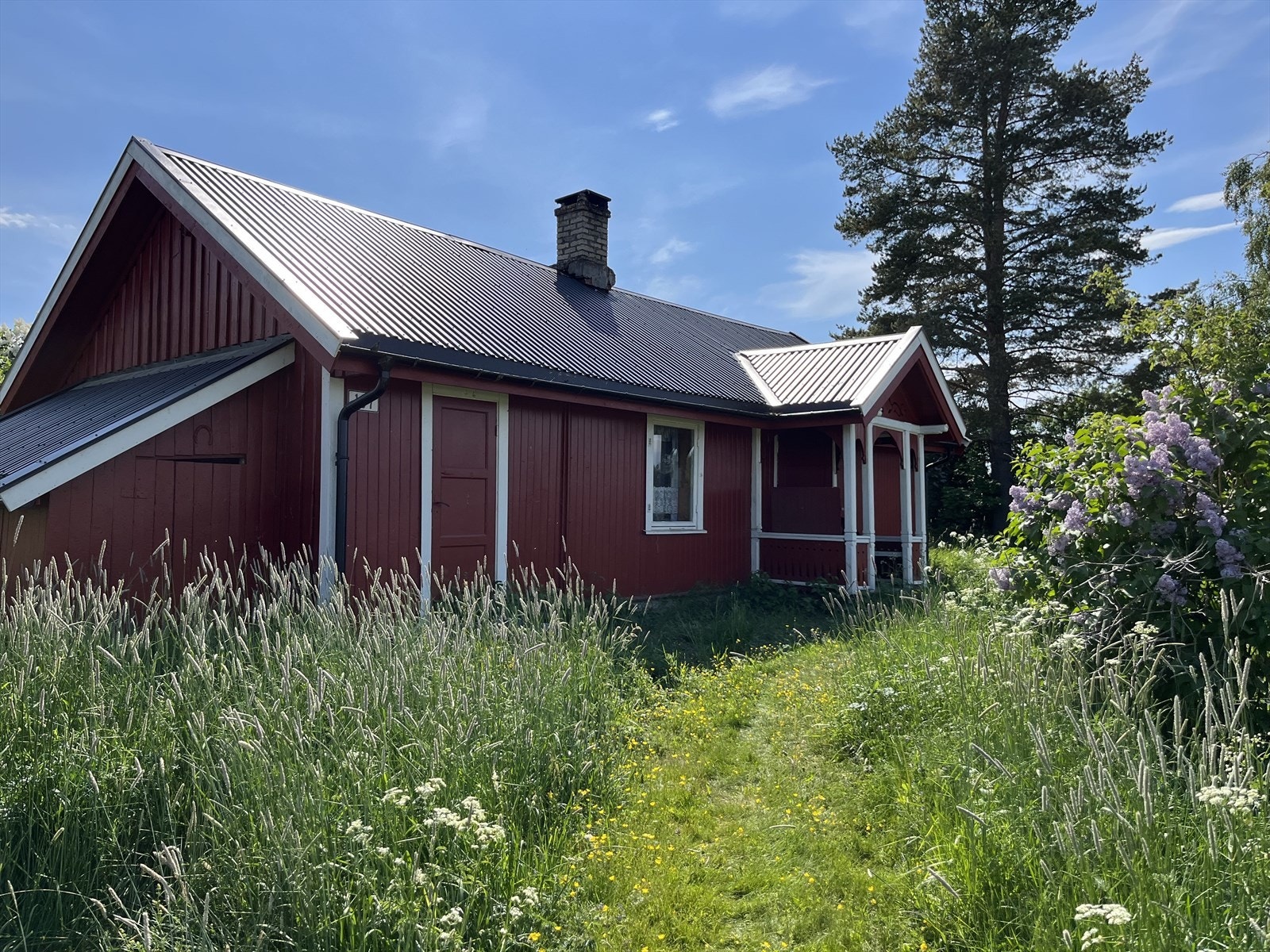 Tradisjonell bindingsverkskonstruksjon med bordkledning og et overbygget inngangsparti i tre. Galleribilde