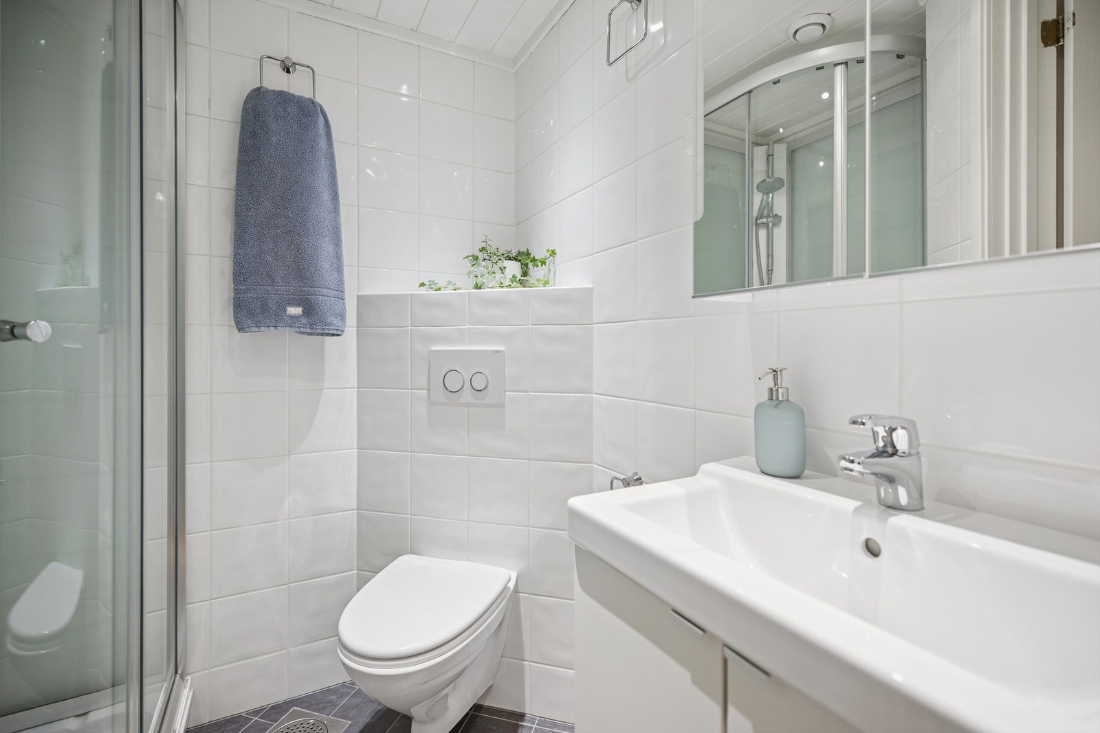 Pent flislagt bad med gulvvarme, vegghengt servantinnredning, dusjkabinett og vegghengt toalett. Galleribilde