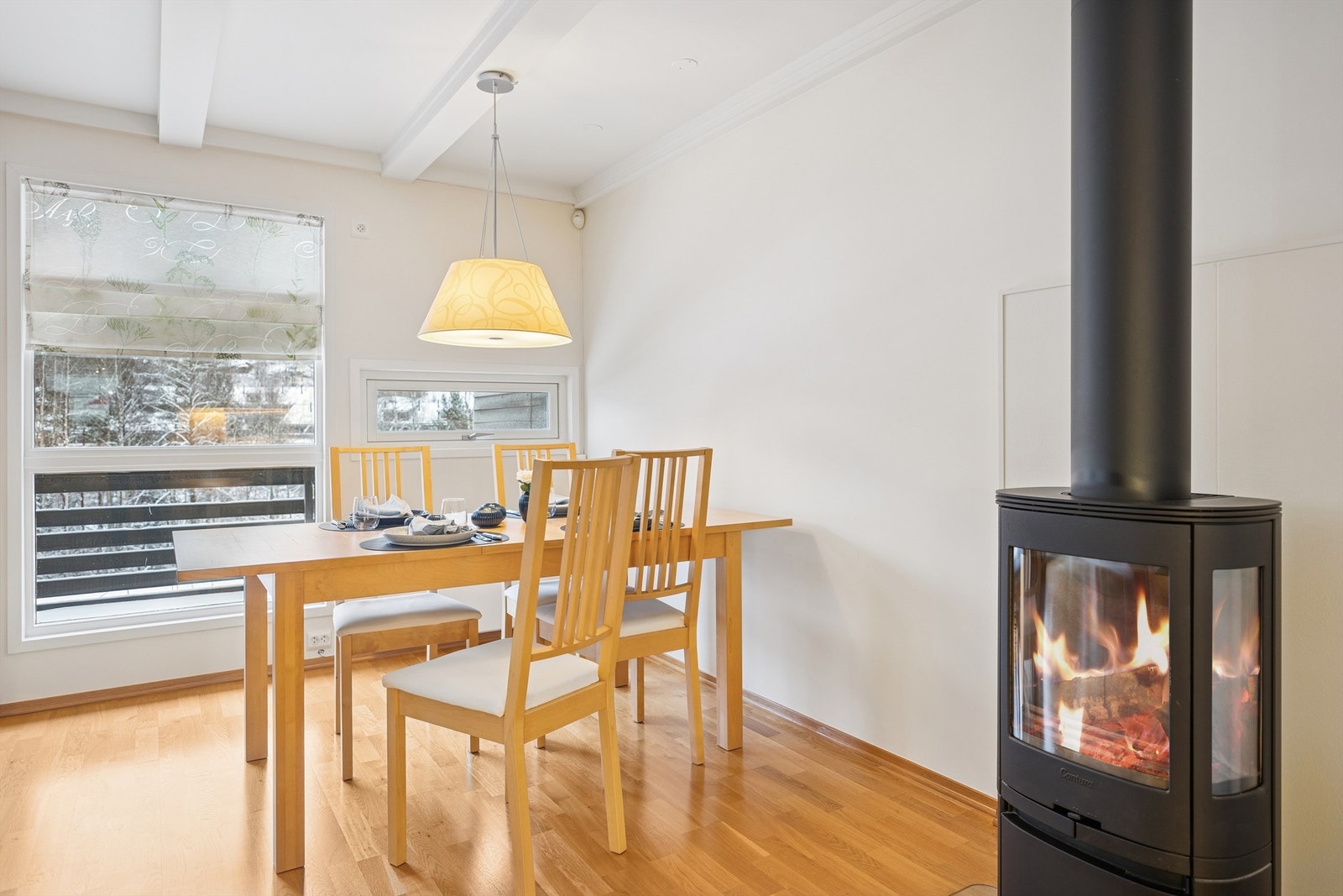 Stuen får godt med naturlig lys fra store vinduer, og den moderne peisovnen bidrar til en koselig og varm atmosfære. Galleribilde