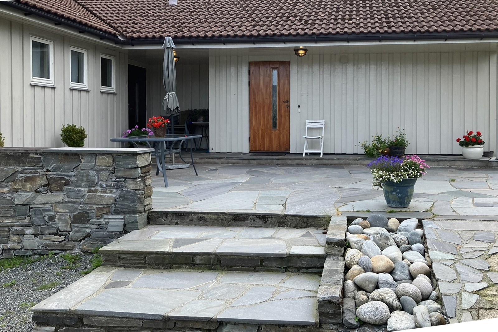 Privat foto: Her er det skiferbelagt gårdsrommet i hyggelig sommerpreg med blomster i krukker. Galleribilde