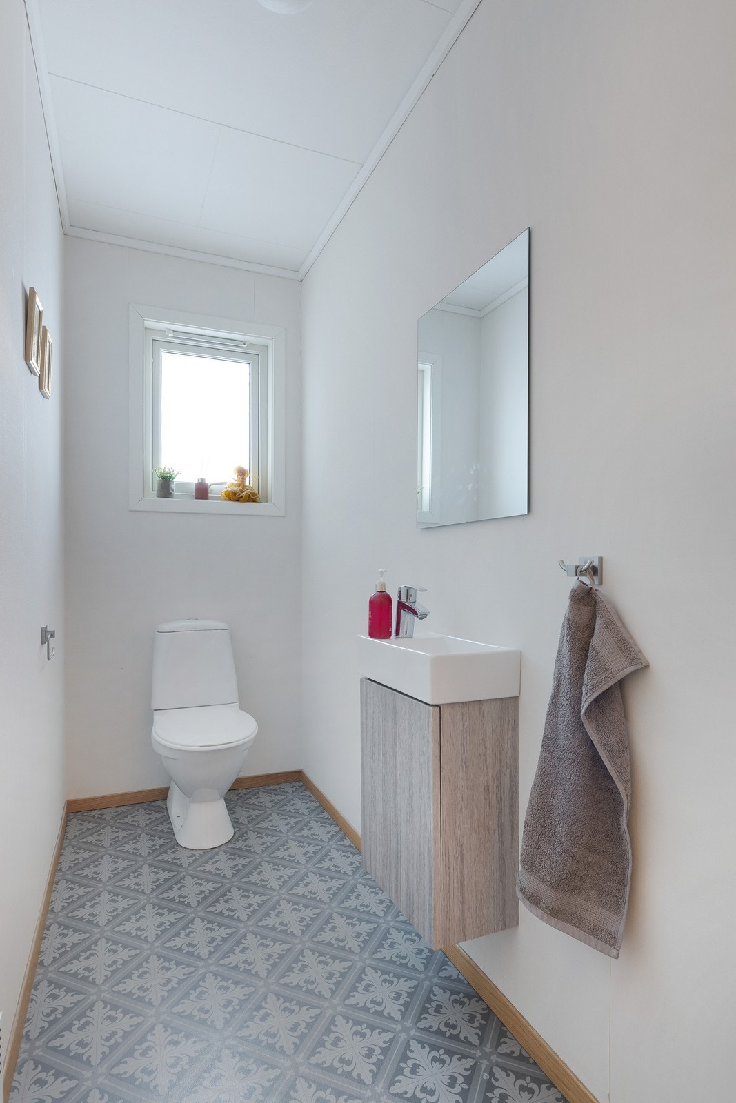 Praktisk og lyst gjestetoalett med stilrent gulv og enkel innredning. Galleribilde