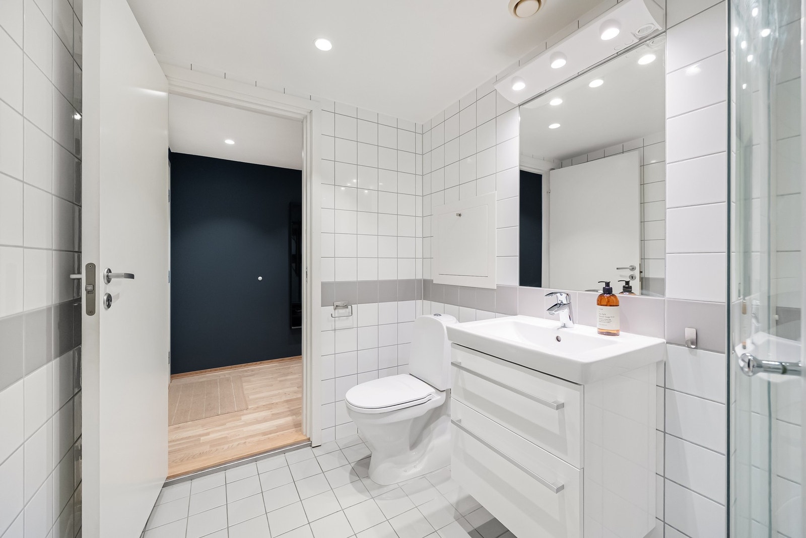 Veggmontert servantinnredning med heldekkende vask og ett greps armatur i krom, gulvstående toalett samt opplegg for vaskemaskin. Galleribilde