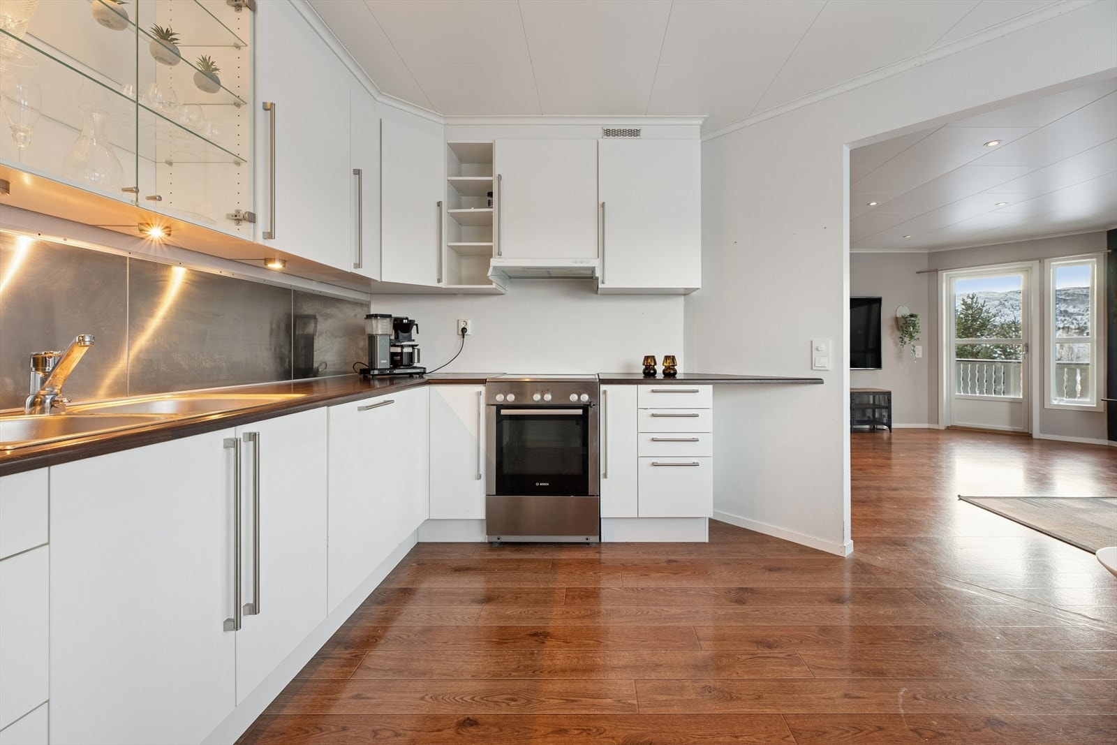 Kjøkkenet har innredning med slette hvite fronter og laminat benkeplate. Galleribilde