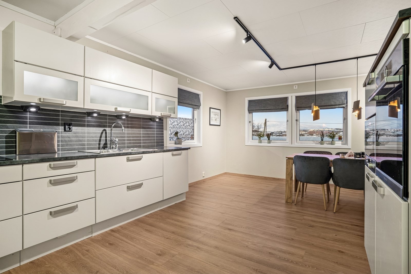 Innholdsrikt og stort kjøkken med hvite slette fronter og medfølgende hvitevarer Galleribilde