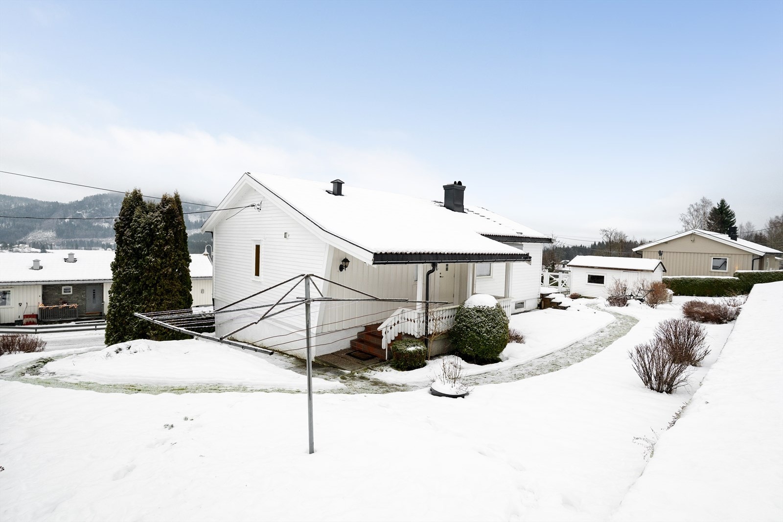 Tomten ligger i skrånende terreng og er pent opparbeidet med plen og variert beplantning. Galleribilde