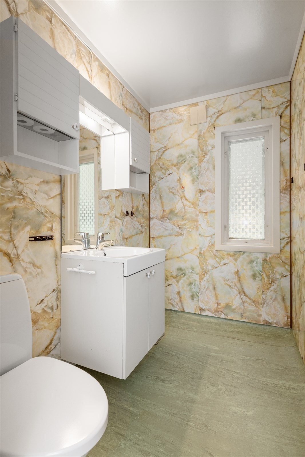 Toalettrommet innehar toalett og servantinnredning med skap og speil. Det er ellers et blandebatteri på vegg, og det er montert nyere reflektorovn. Galleribilde