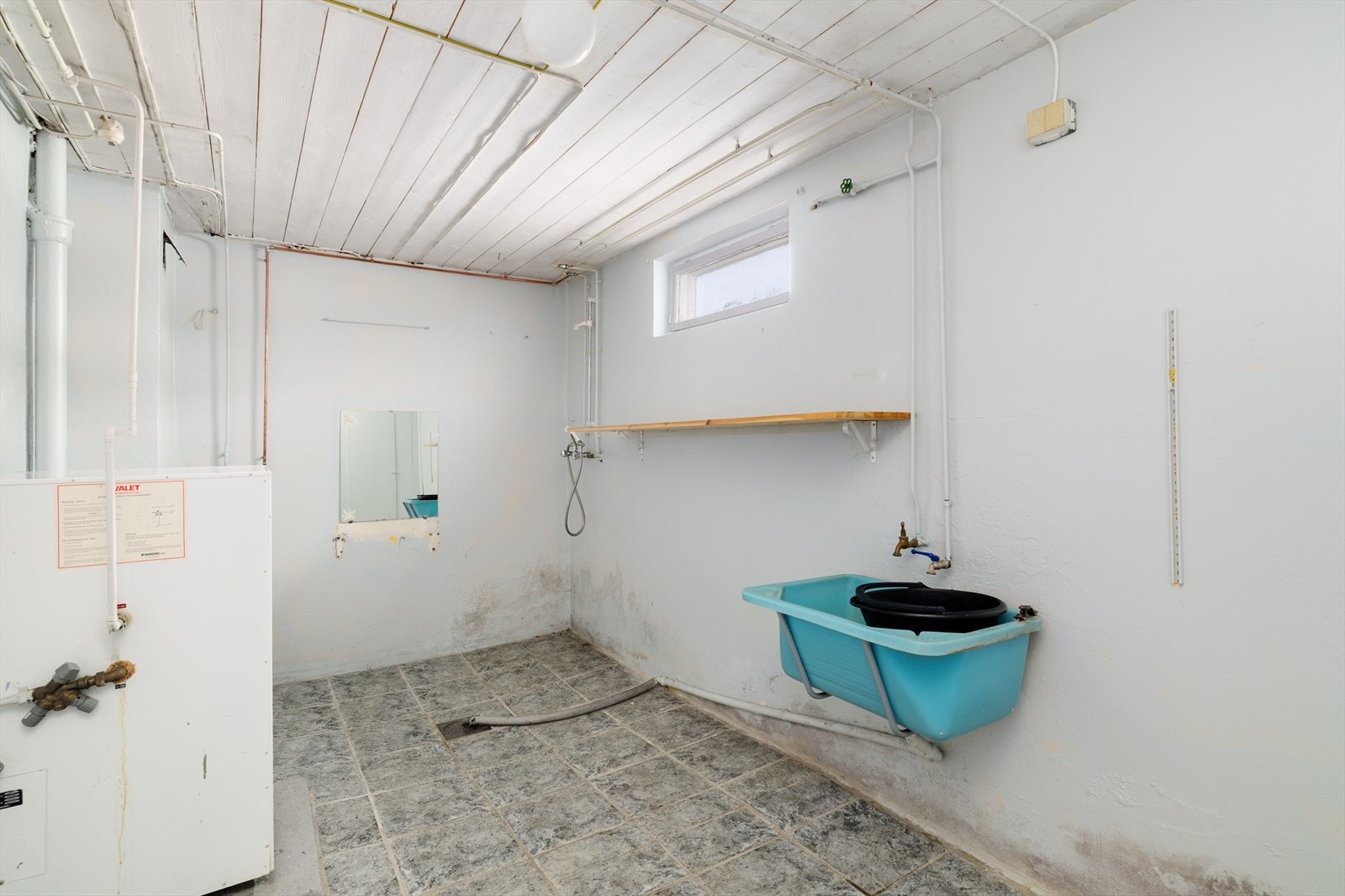 Eldre vaskekjeller med opplegg for dusj, utslagskum, varmtvannstank og hovedstoppekran. Galleribilde