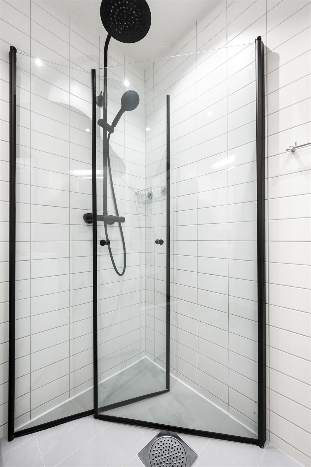 Badet er innredet med et praktisk dusjhjørne med svingbare glassdører og vegghengt klosett. Galleribilde