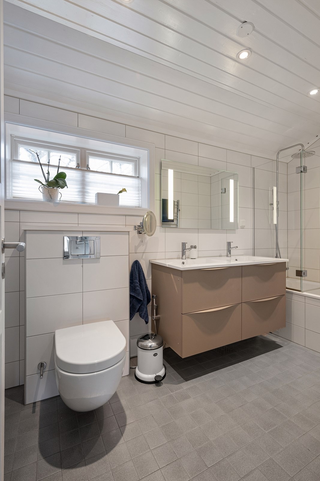 Delikat bad med badekar med regnfallsdusj, dobbel servant med skuffer, speil og wc. Galleribilde