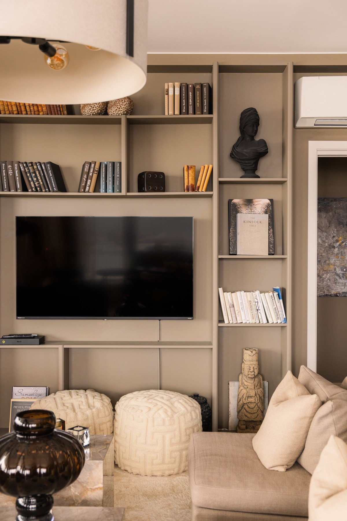 I stuen er det stilrene, plassbygde hyller som rammer inn TV-en på en elegant måte, med god plass til bøker og personlig interiør. Galleribilde