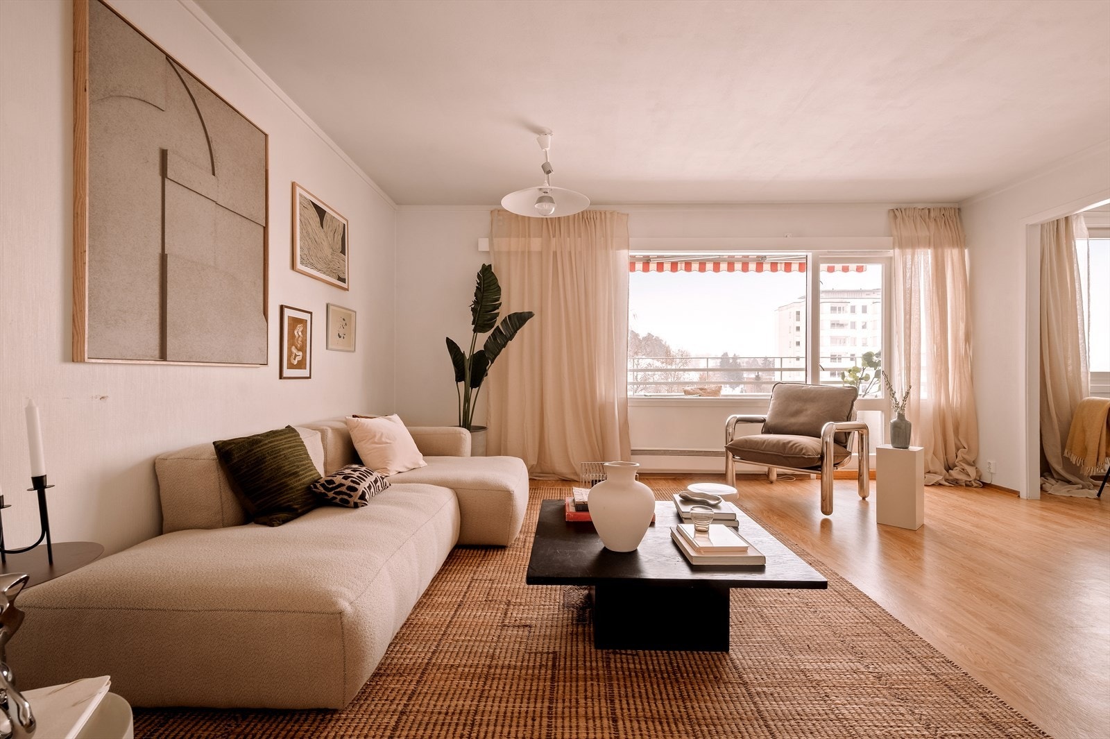 Store vindusflater og utgang til balkong sørger for rikelig med naturlig lys, samtidig som stuen byr på en hyggelig utsikt mot grønne omgivelser. Galleribilde