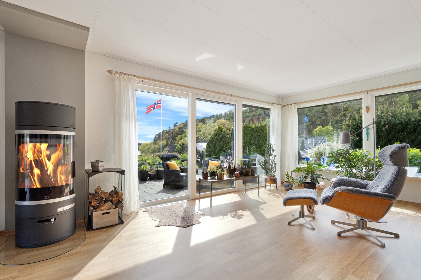 Lys og innbydende stue med store vindusflater som slipper inn rikelig med naturlig dagslys. En peisovn er plassert sentralt i rommet og gir både varme og hygge til hele etasjen - perfekt for kjølige kvelder. Galleribilde