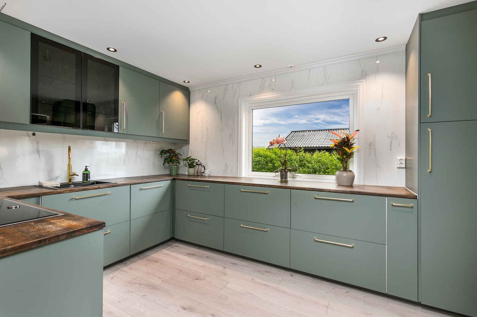 Kjøkkeninnredning med glatte fronter i tidsriktig farge, med håndtak. Benkeplate i heltre med nedfelt kum. Galleribilde