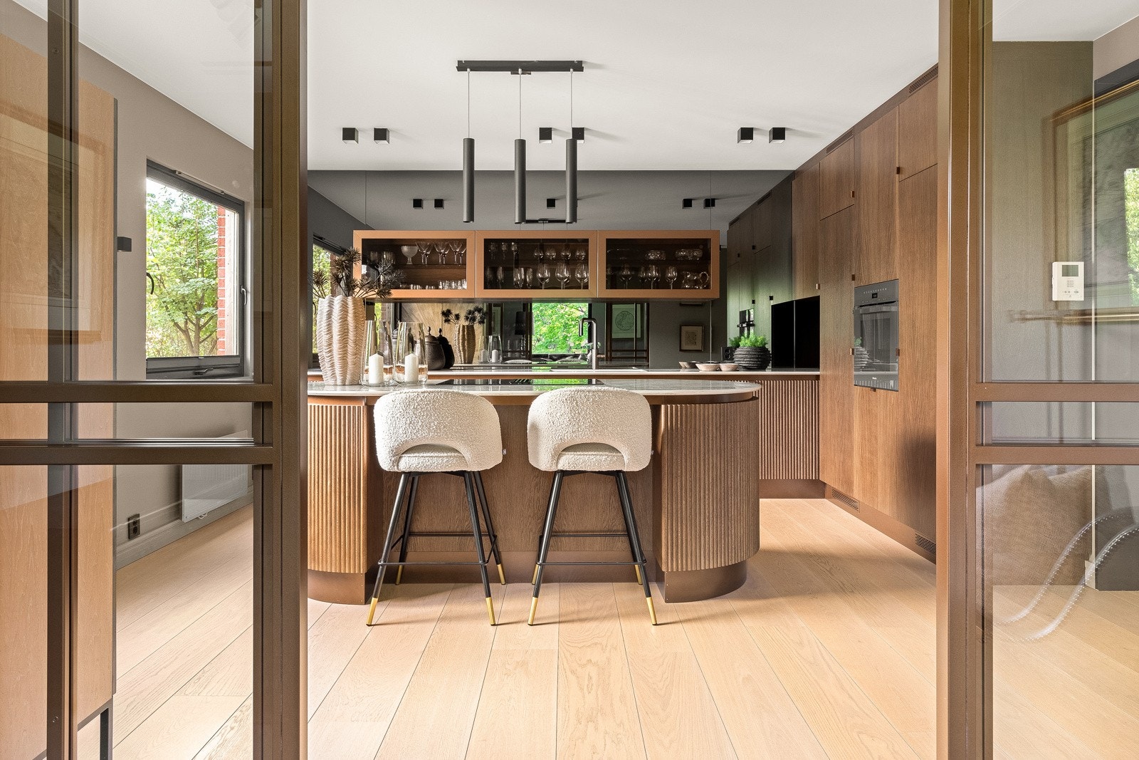 Det elegante, snekkerbygde kjøkkenet ligger i åpen løsning mot stuen, med 1-stavs eikeparkett og lyse vegger som rammer inn innredning i smoked oak og vitrineskap. Galleribilde