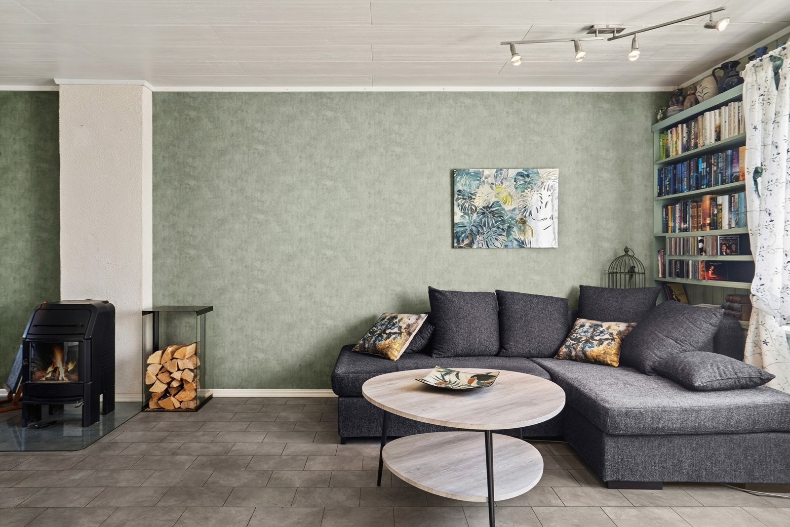 Sofa og TV-møbel har sin naturlige plassering i denne enden av stuen. På de kaldeste dagene kan det fyres med ved i peisovnen. Galleribilde