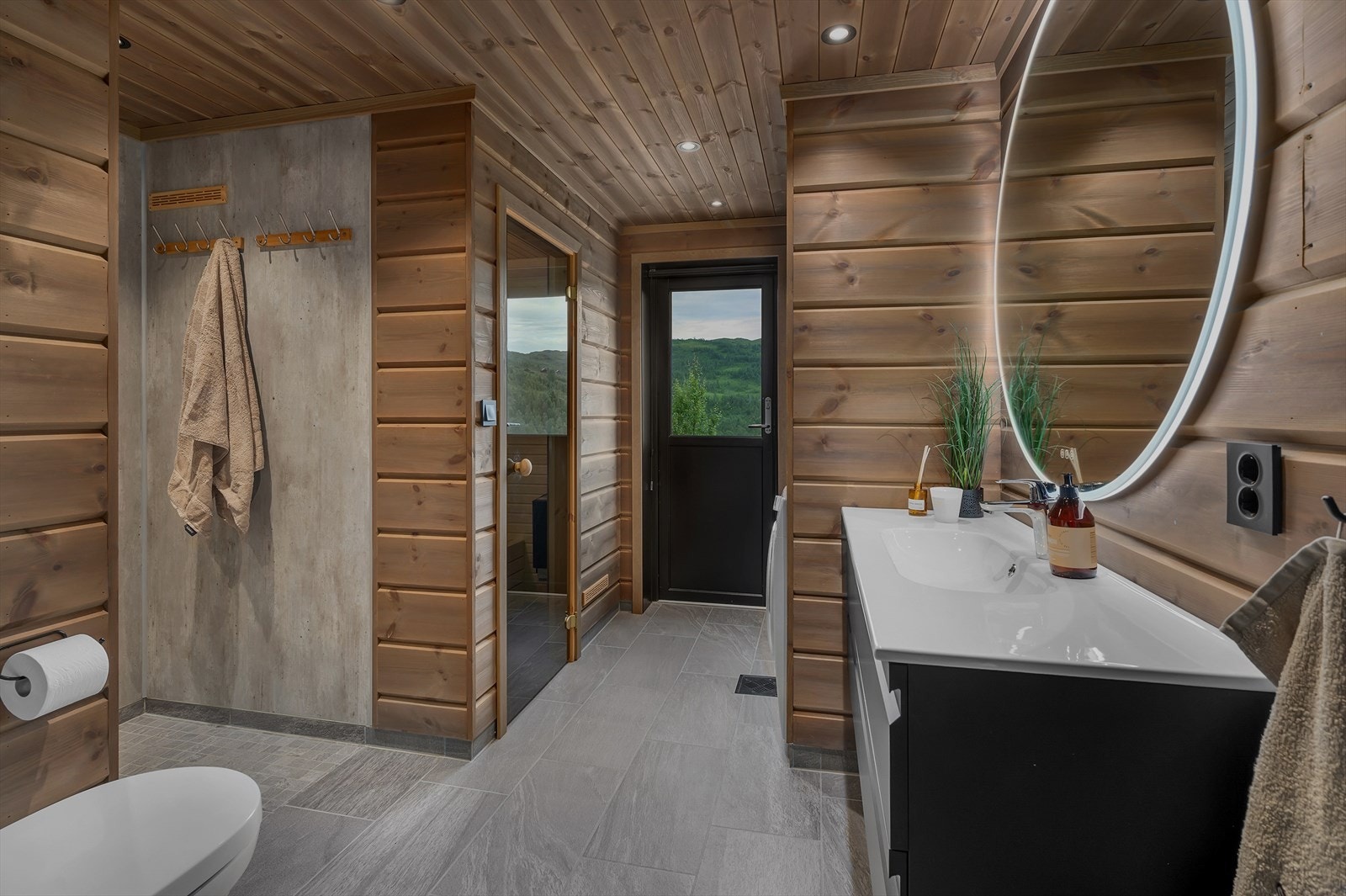 Badet er av god storleik og inneheld nedfelt servant med underskuffer, spegel med lyslist, vegghengt klosett, plassbygd dusjnise, opplegg for vaskemaskin og praktiske oppbevaringshyller. Galleribilde