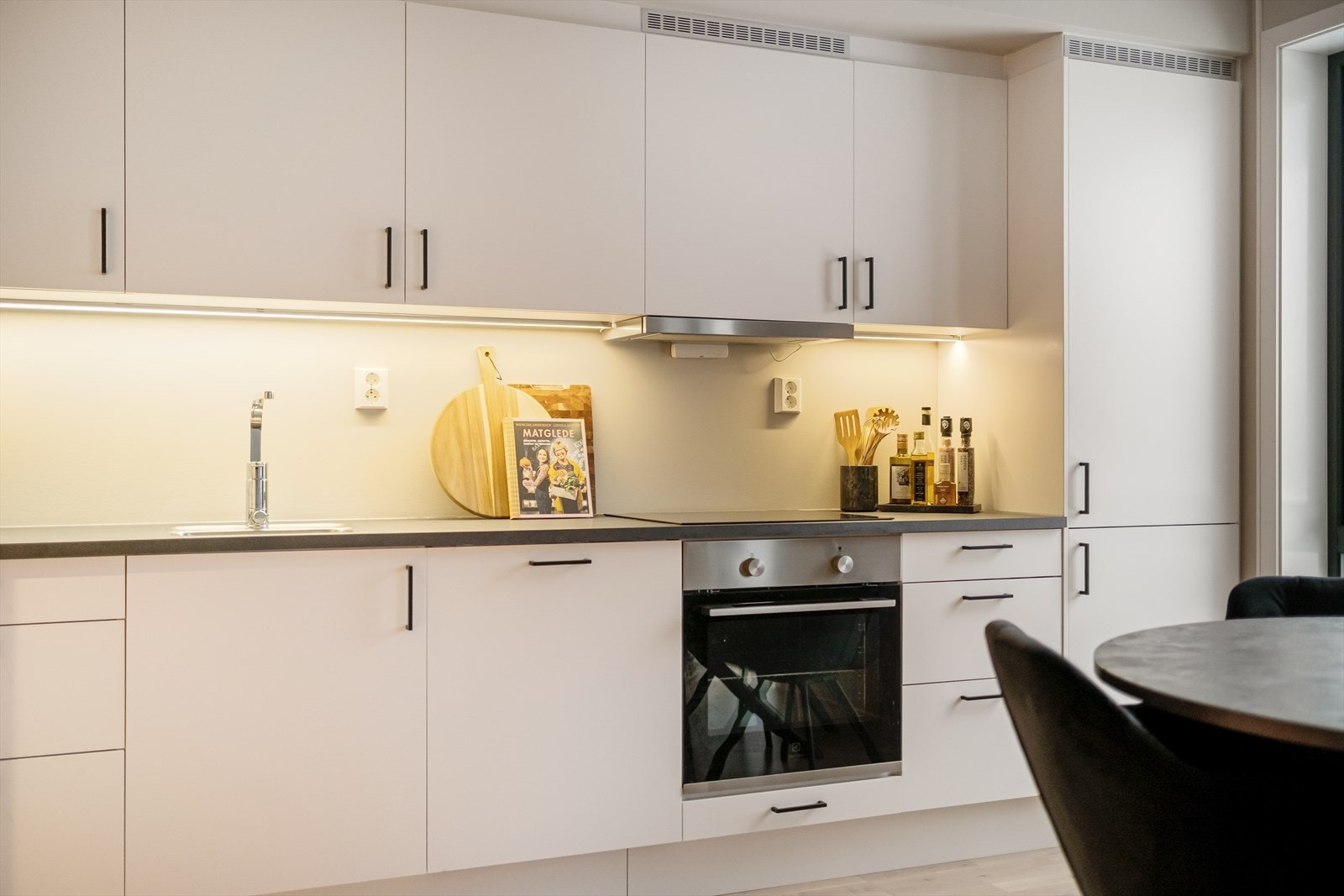 Moderne kjøkken med foring helt opp til himling og integrerte hvitevarer. Galleribilde