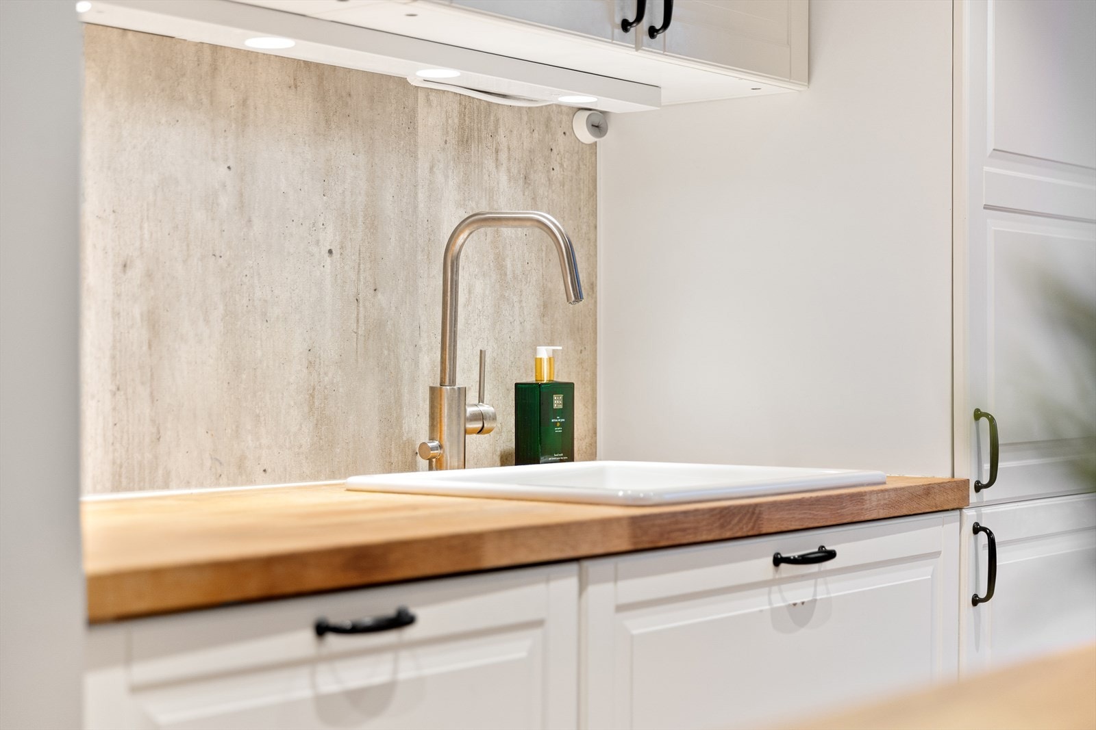 Detaljer som underlimt porselensvask og moderne armatur understreker kjøkkenets kvalitet. Galleribilde