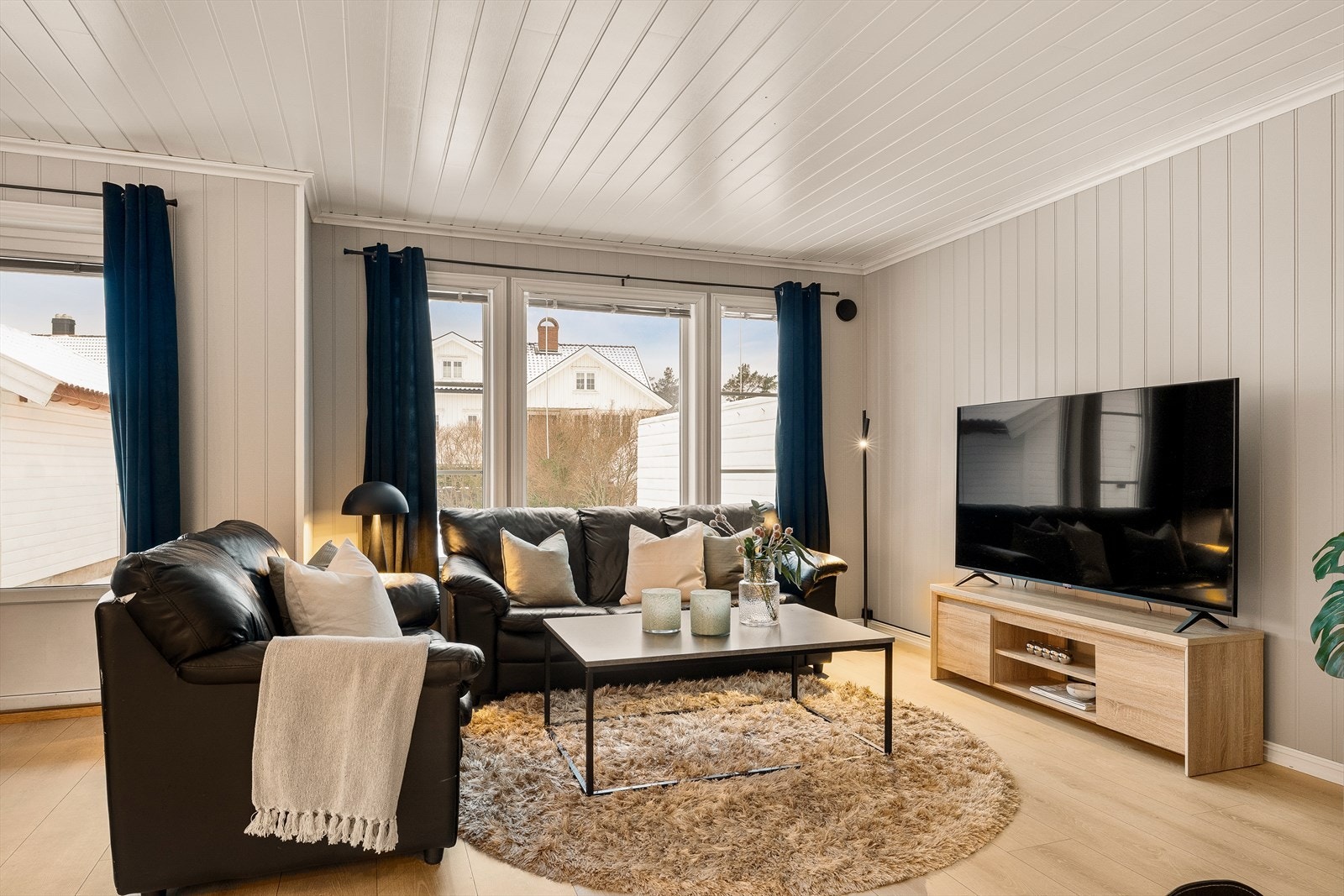 Lys stue med laminat på gulv og malte panel i tak og vegger Galleribilde