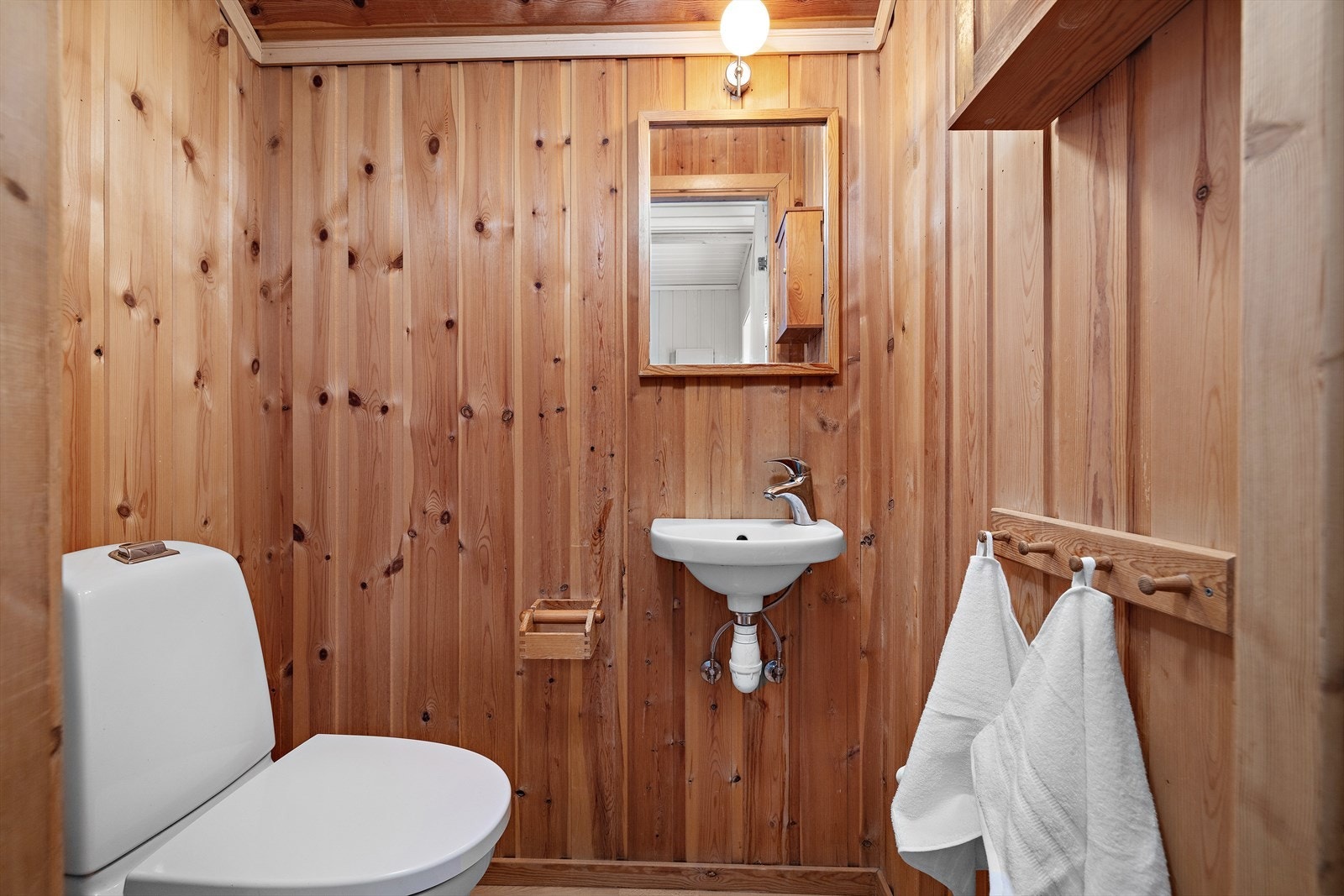Praktisk toalettrom i første etasje med trepanel på vegger og i himling. Galleribilde